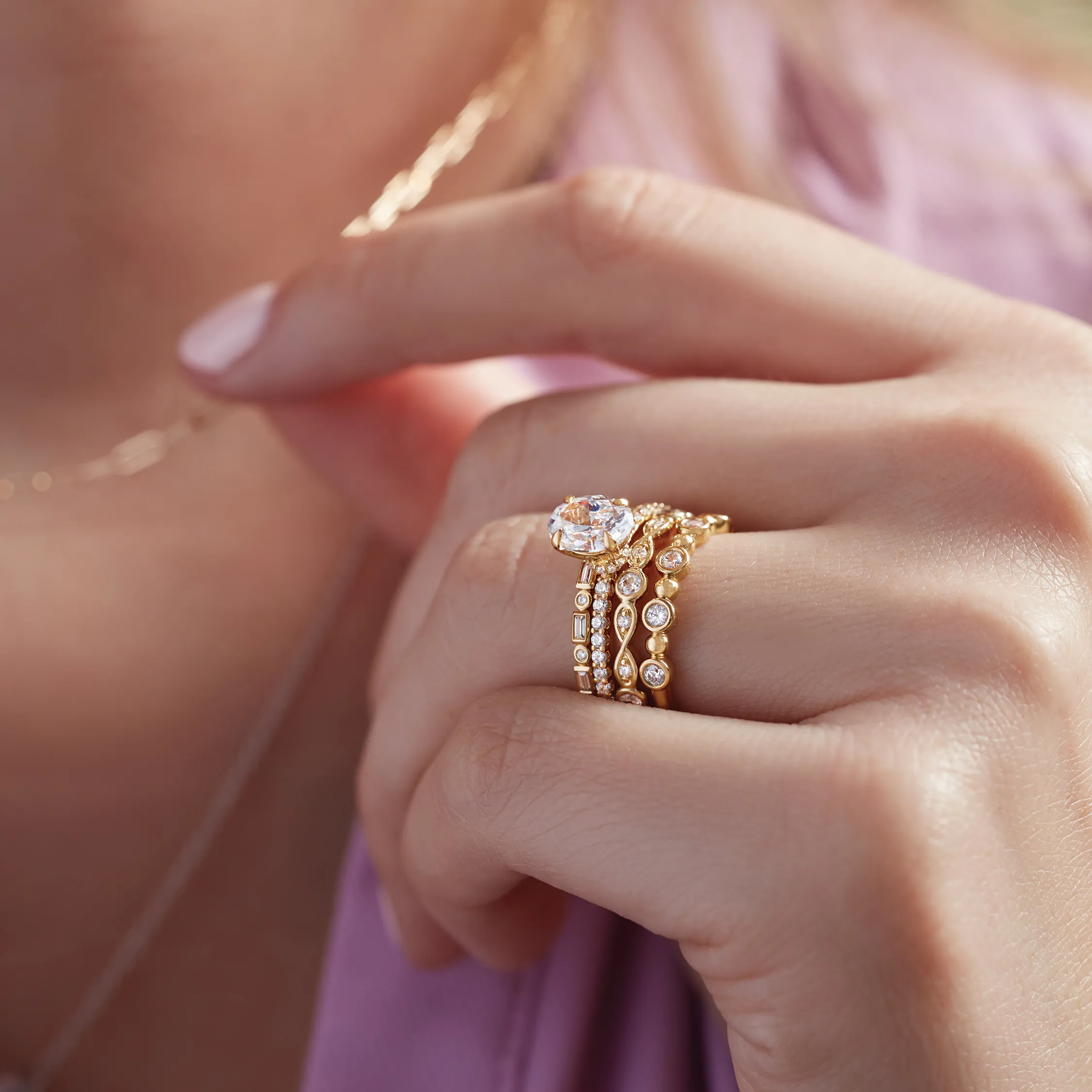 A woman with curly hair showcases a stunning ring, smiling against a warm, soft background.