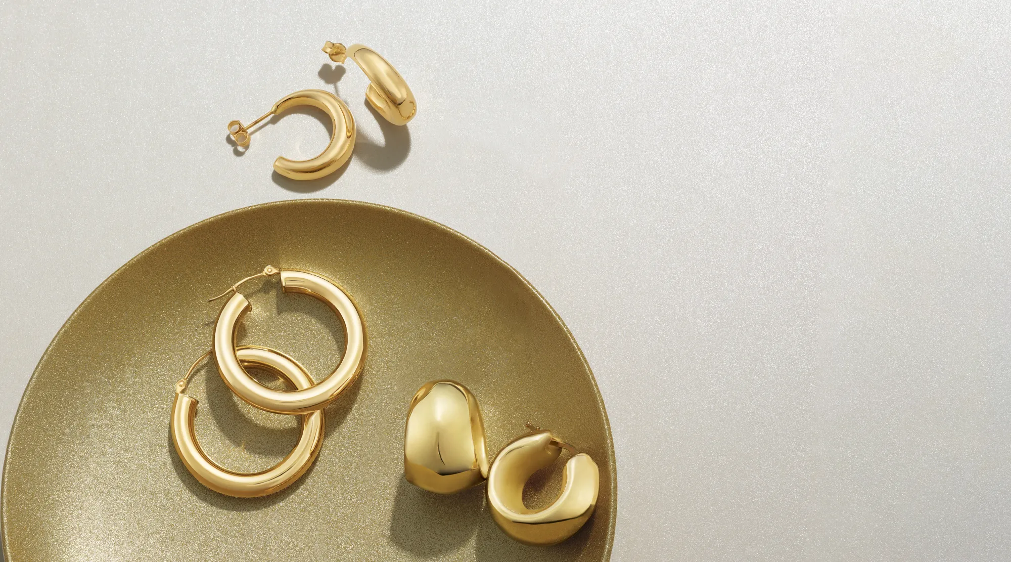 Gold hoop earrings displayed on a gold plate, showcasing elegant jewelry.