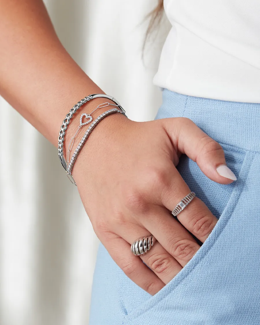 Silver bracelets and rings worn on a hand, showcasing stylish jewelry.