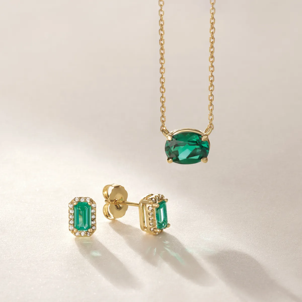 Emerald necklace and earrings set in gold, showcasing elegant green gemstones. 