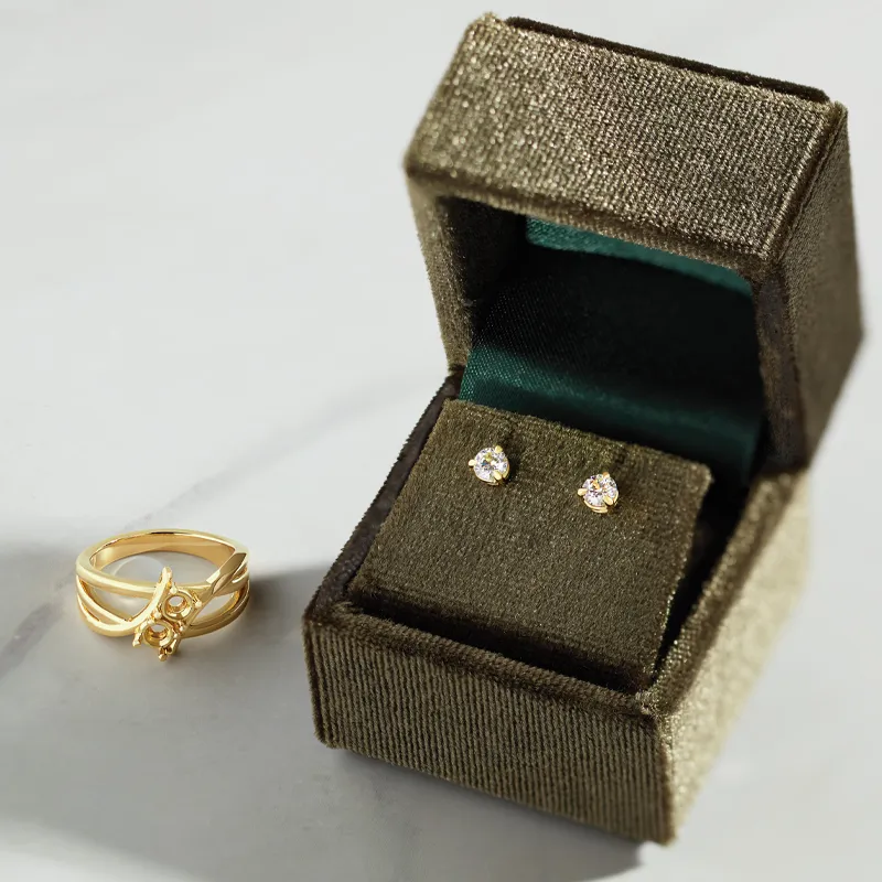 Gold ring and diamond stud earrings in a luxurious box, showcasing customizable jewelry options.