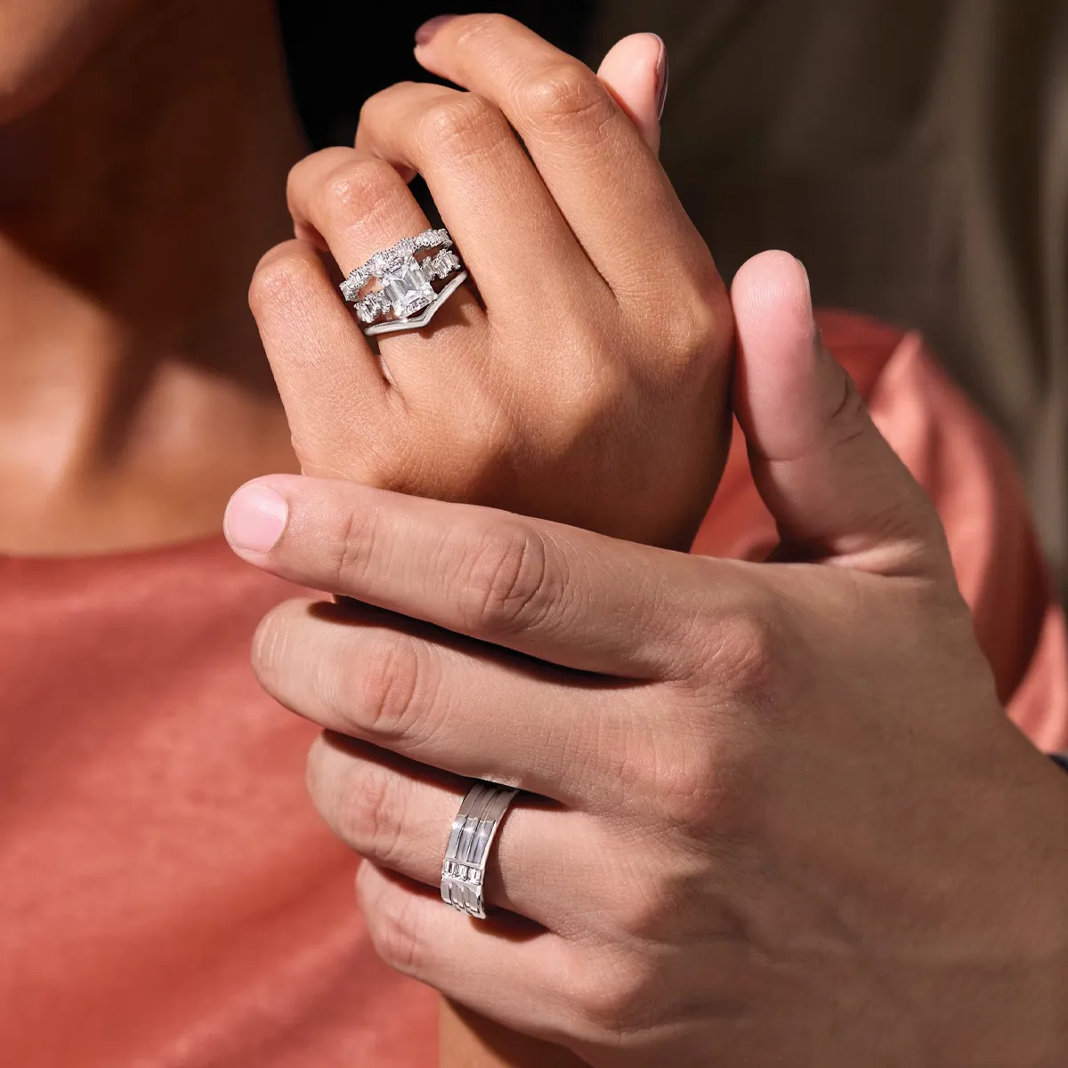 A couple's hands showcasing a diamond engagement ring and wedding band, symbolizing love and commitment.