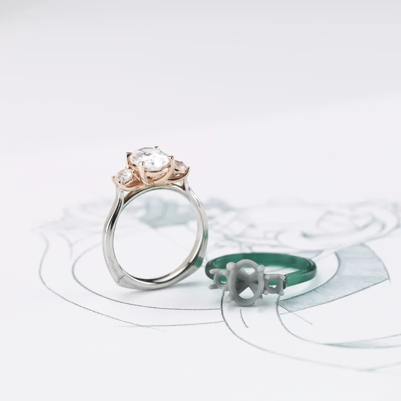 Custom engagement rings displayed with a sketch, featuring a diamond ring and a wax model. 