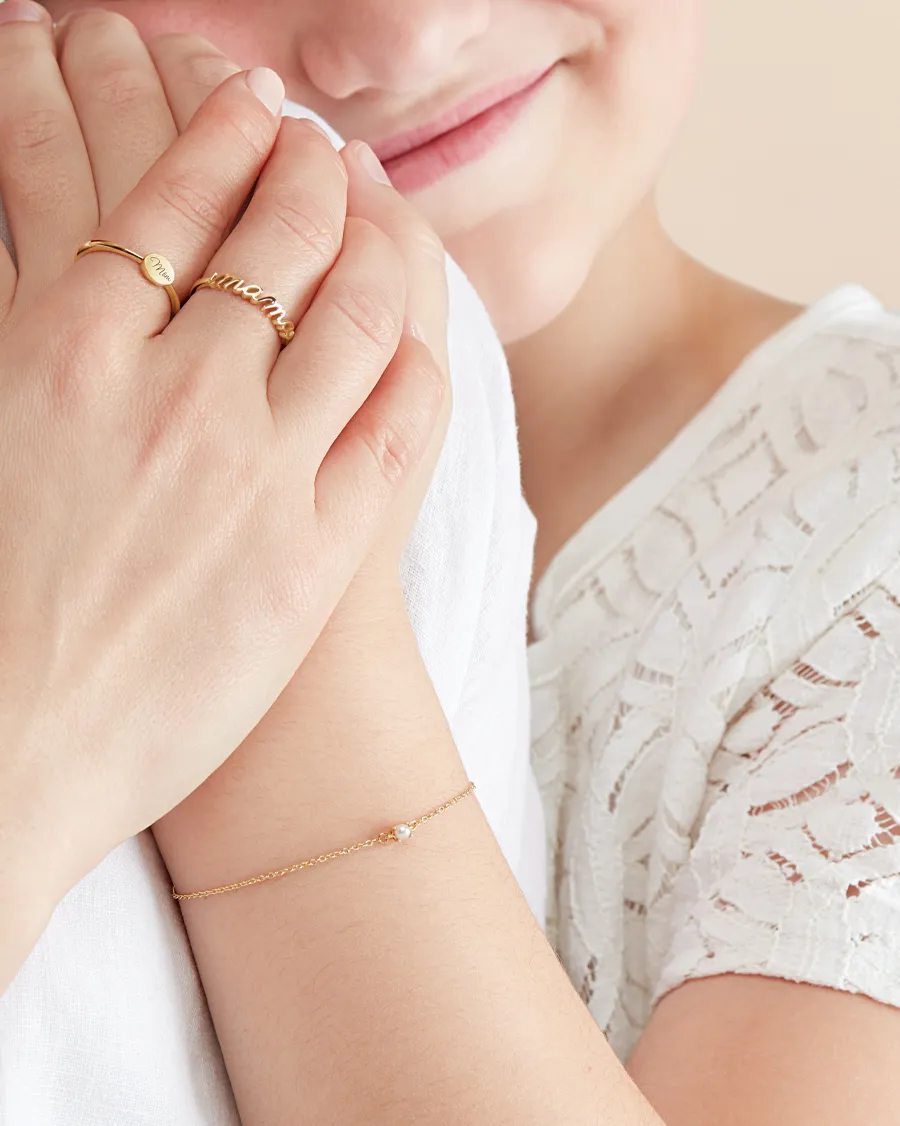 A woman showcases gold rings and a delicate bracelet with pearls, highlighting children's jewelry.