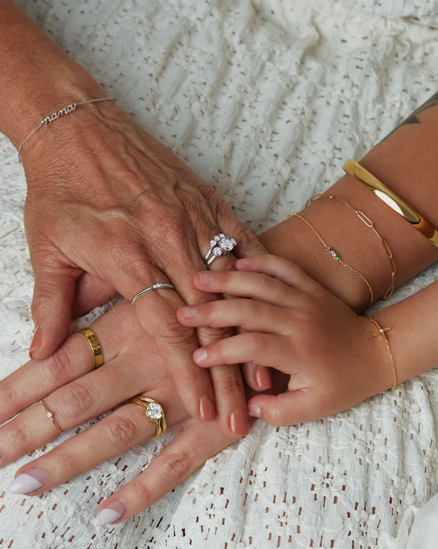 Three generations of hands adorned with rings and bracelets, symbolizing family bonds and love.