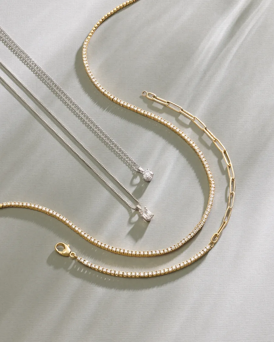 Elegant silver and gold necklaces displayed on a soft surface, showcasing fine jewelry.