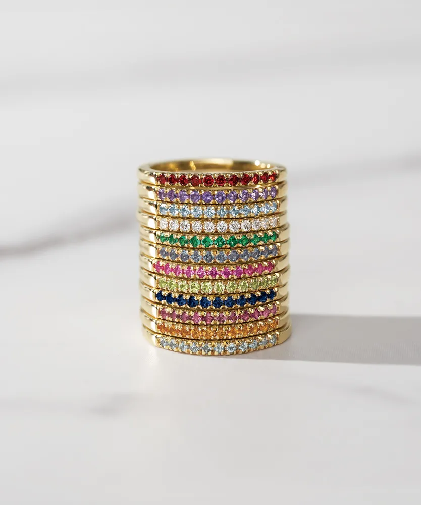 Colorful stacked rings with gold bands and various gemstones, showcasing a vibrant jewelry collection.