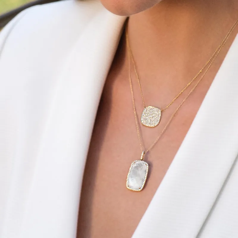 Gold layered necklaces featuring a sparkling pendant and a stone charm, worn on a model's neck.