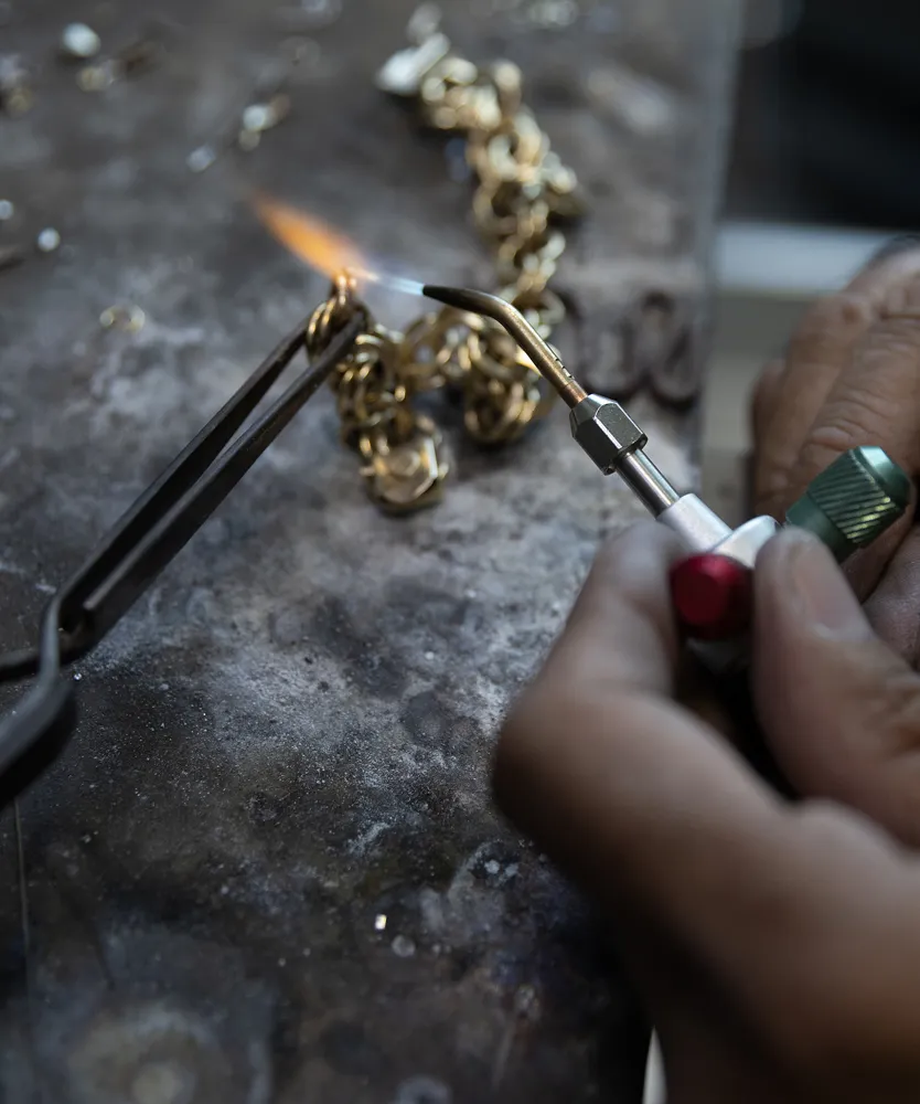 A jeweler uses a torch to heat a gold chain, showcasing the jewelry-making process at Ambassador Diamond Jewelers in Tucson.