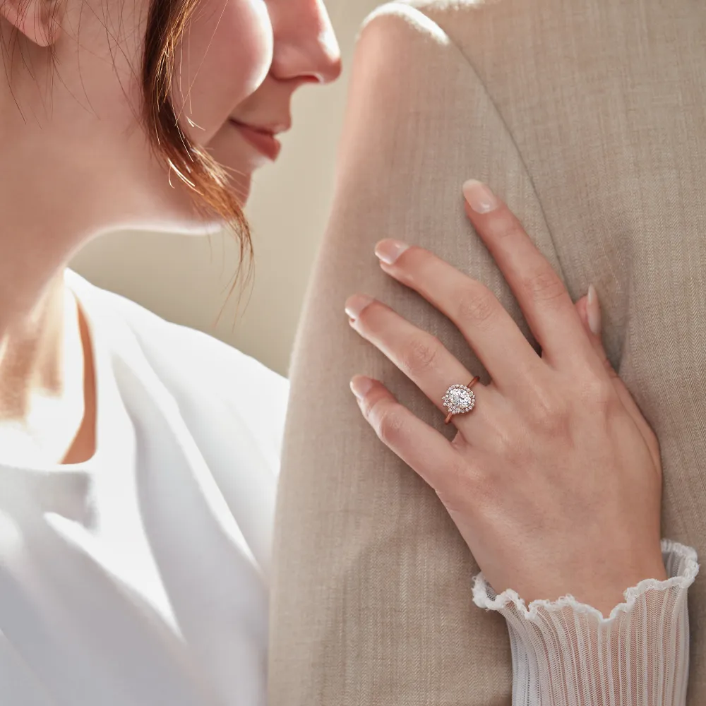 A woman shows off her engagement ring while leaning close to a partner, highlighting the ring's sparkle and elegance.