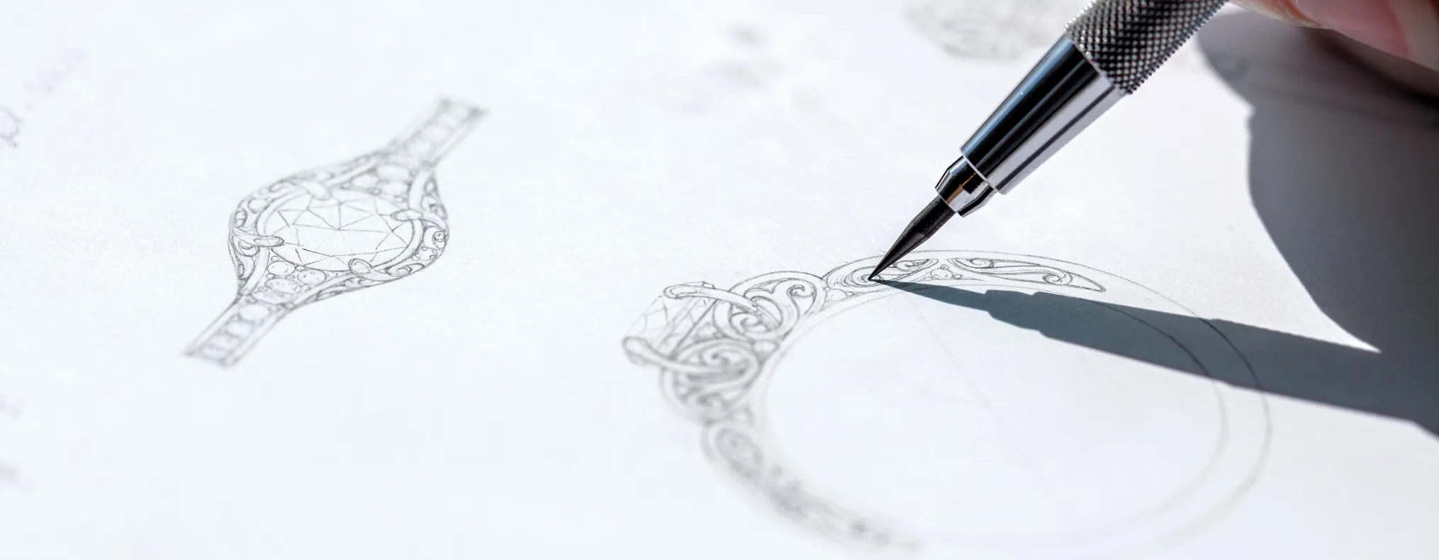 A hand sketches intricate jewelry designs on paper, showcasing creativity for personalized engagement rings.