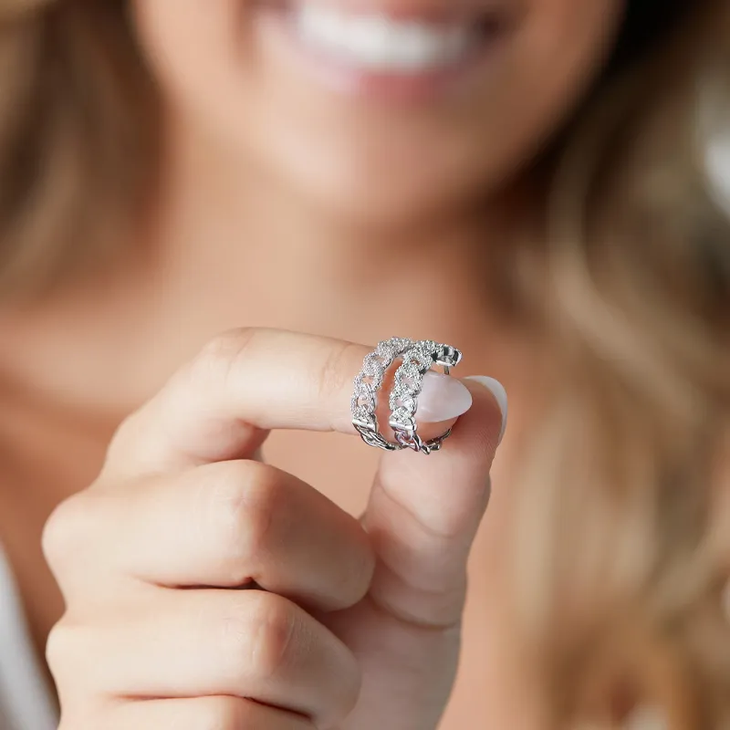 A woman holds a sparkling diamond earrings, showcasing the intricate design and shine, with a bright smile in the background.