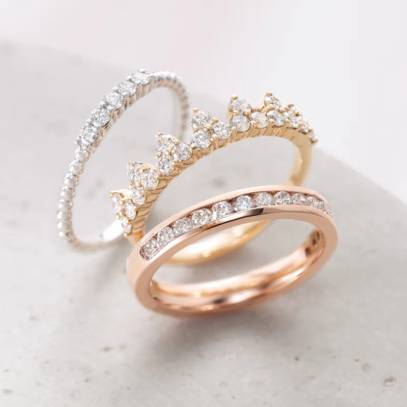 Three elegant diamond rings in white gold and rose gold, showcasing intricate designs and sparkling stones.