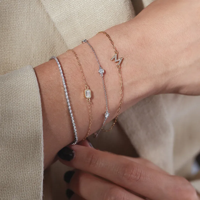 Four elegant bracelets on a wrist, featuring diamonds and gold accents.