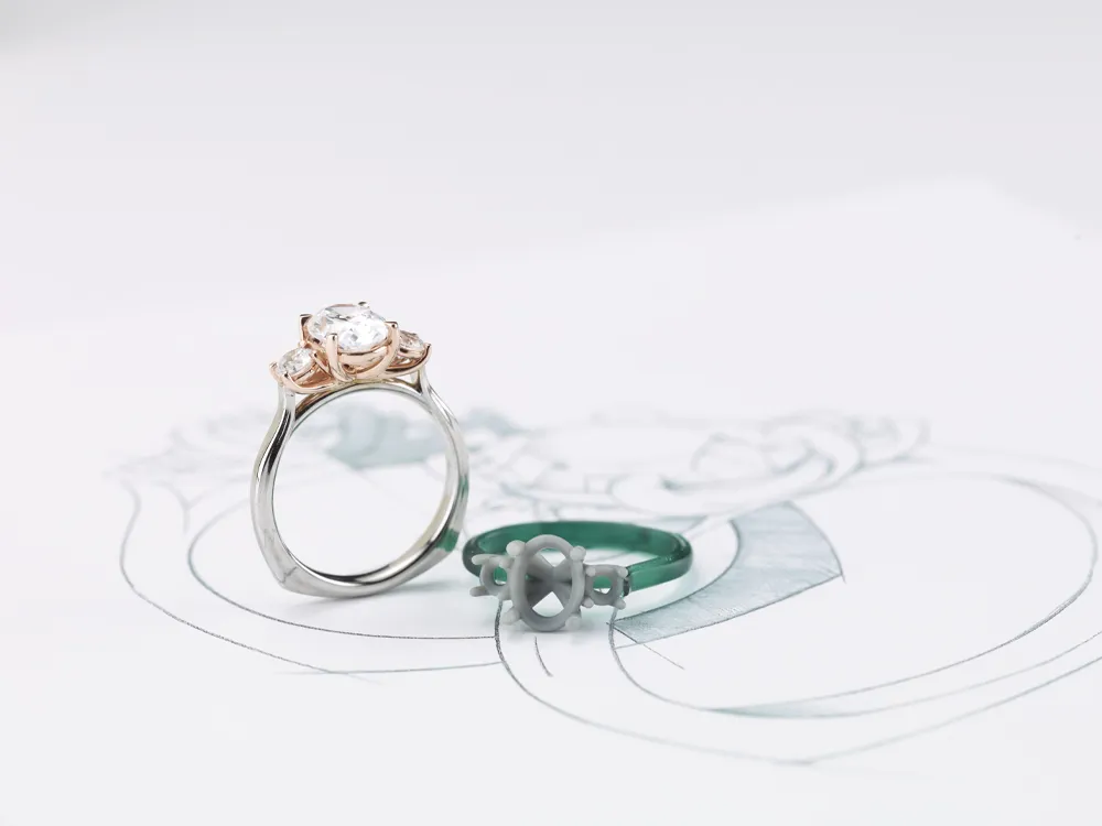 A diamond engagement ring and a green band ring on a sketch, showcasing custom jewelry design.