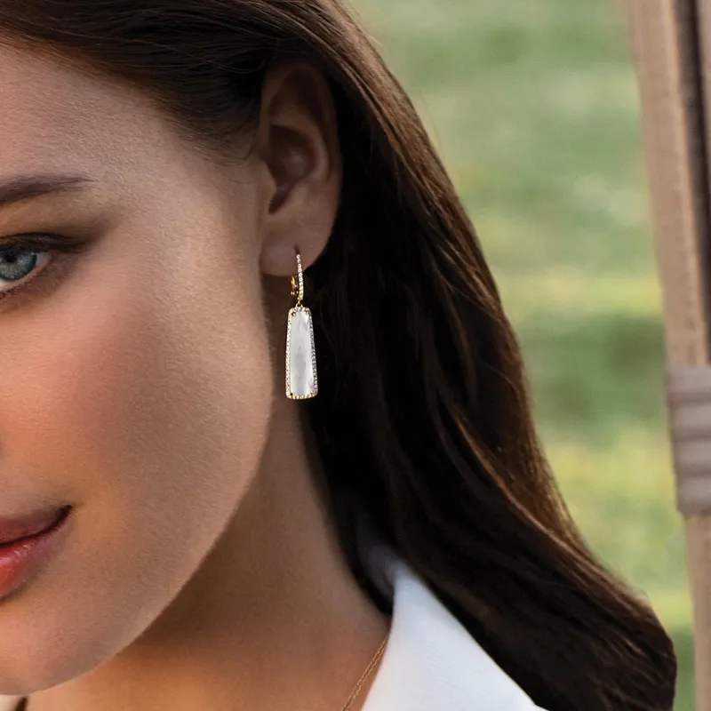 Elegant woman wearing gold and white earrings, showcasing fine jewelry from Ambassador Diamond Jewelers in Tucson.