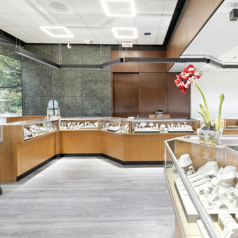 Jewelry display area at Ambassador Diamond Jewelers, featuring elegant pieces and a floral accent.