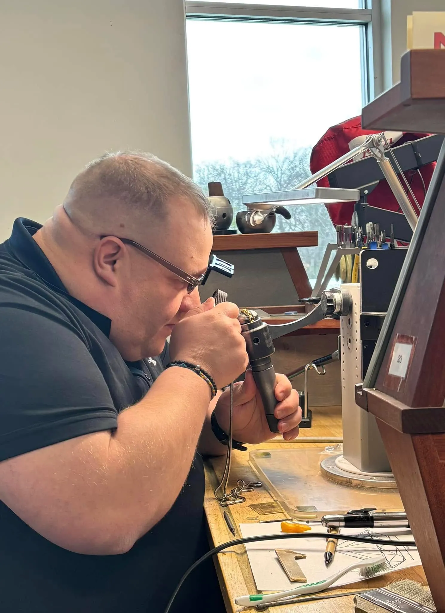 Jeweler inspecting a watch mechanism at Amos Jewelry in Wray, showcasing craftsmanship and attention to detail.