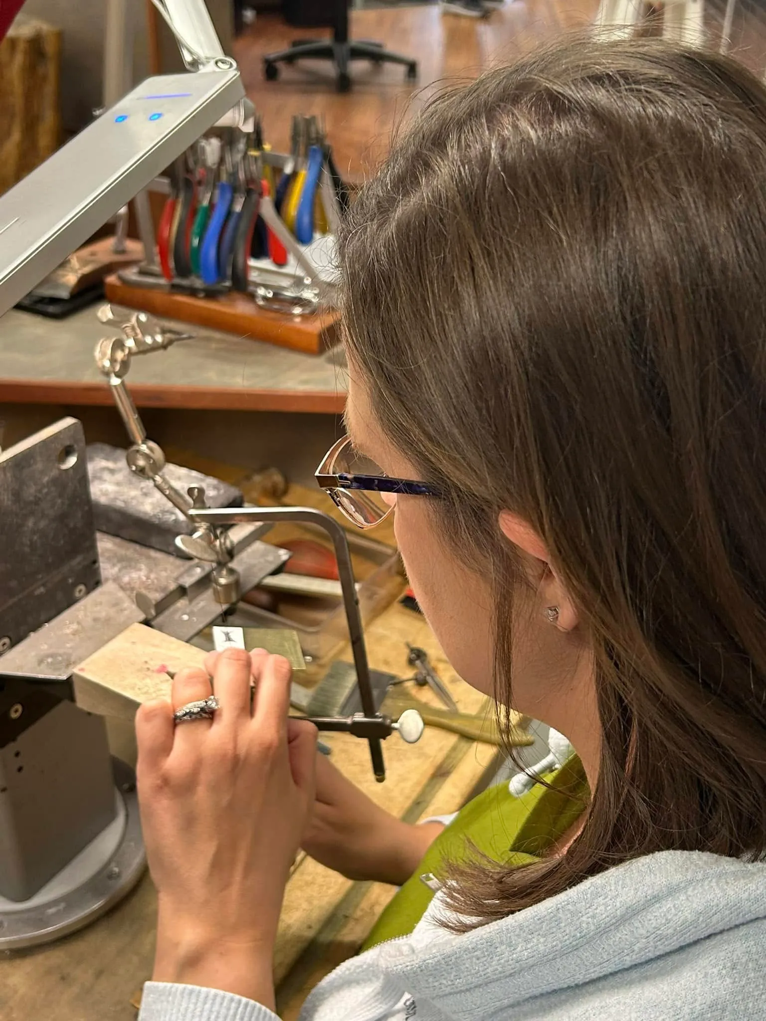 Jeweler working on a piece with tools in a workshop at Amos Jewelry, Wray.
