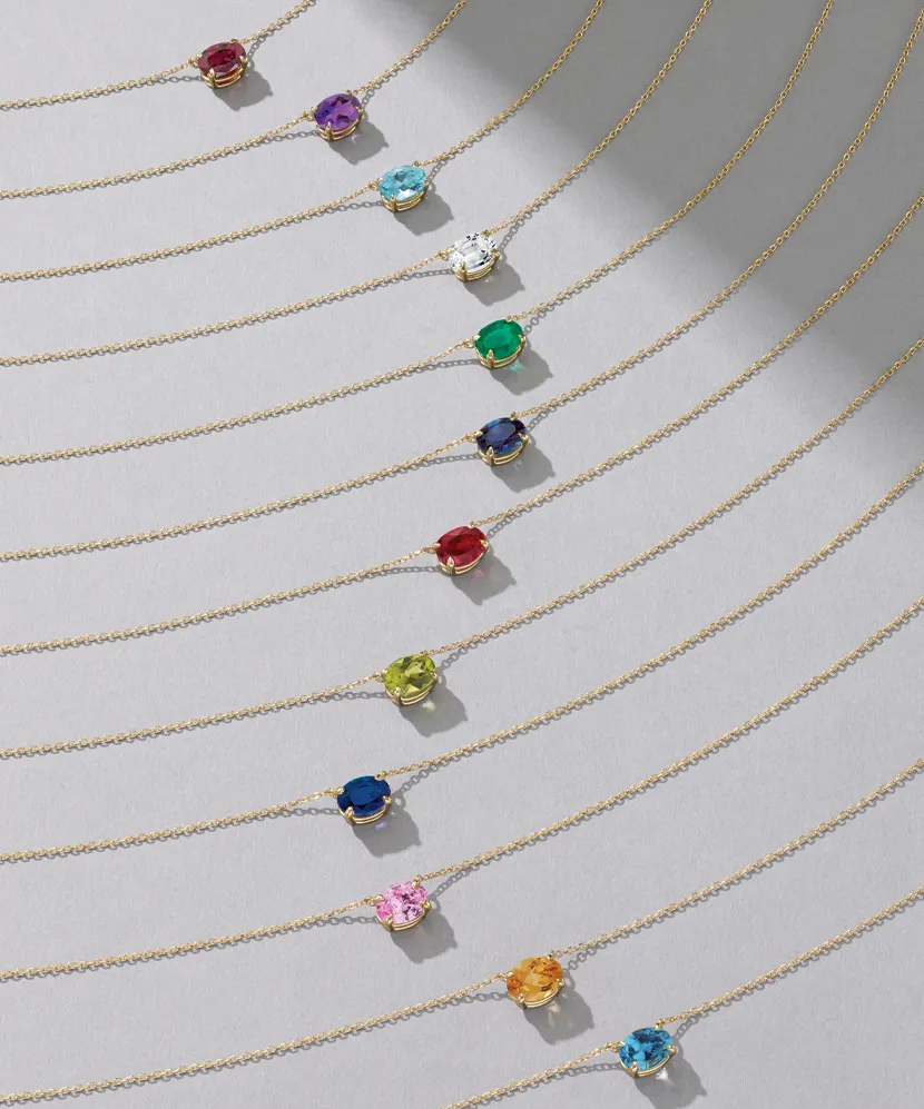 Colorful gemstone necklaces on gold chains displayed cascading in a row. 