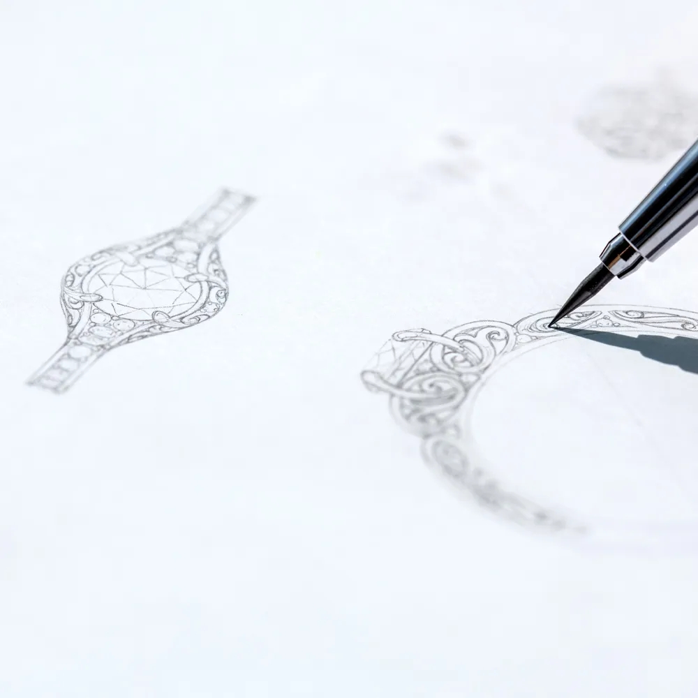 Close-up of a hand sketching intricate jewelry designs on paper for Amos Jewelry in Wray.