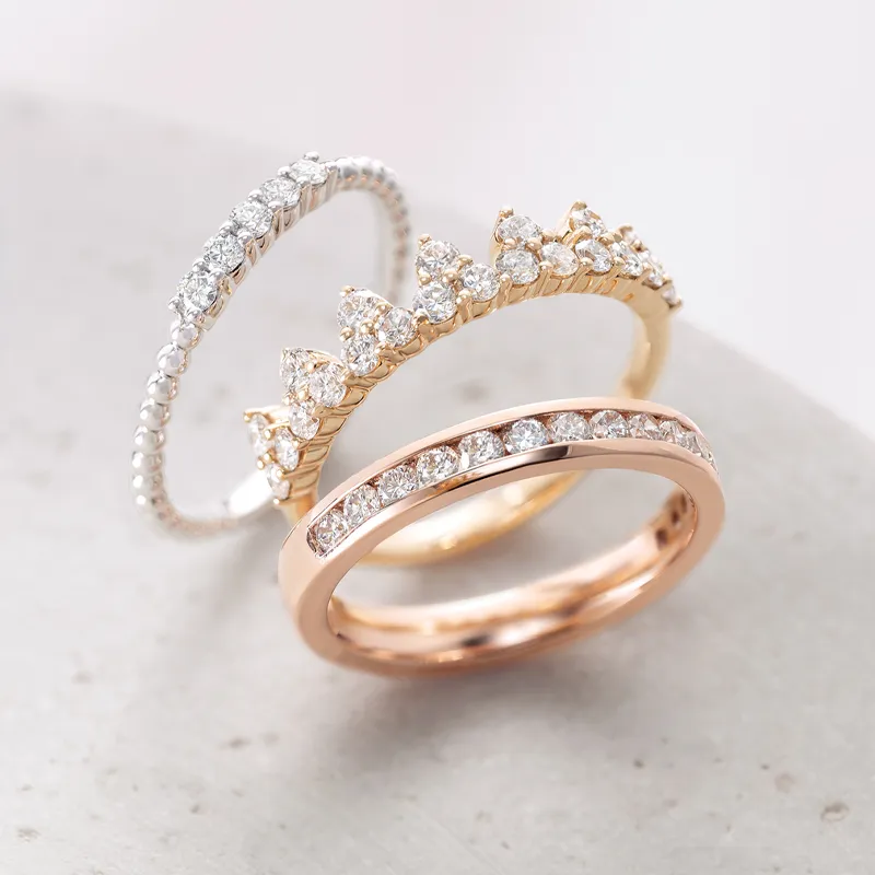 Three elegant diamond fashion rings in white gold, yellow gold, and rose gold, showcasing intricate designs and sparkling stones