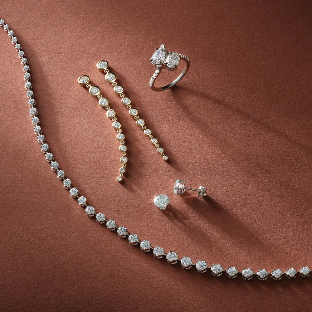 Elegant jewelry collection featuring a diamond necklace, earrings, and a ring on a warm background. 