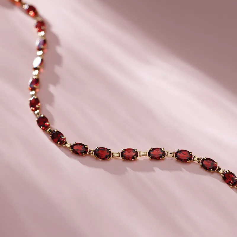 Elegant red gemstone bracelet on a soft pink background, showcasing fine jewelry from Amos Jewelry in Wray.