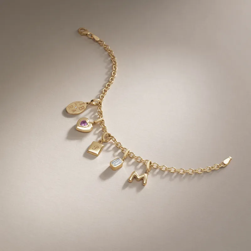 Gold charm bracelet featuring various charms including a heart, lock, and initials.