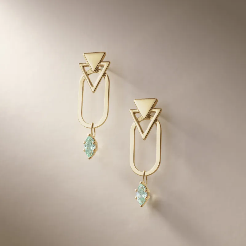 Gold geometric earrings with green-colored gems, displayed elegantly against a soft background.