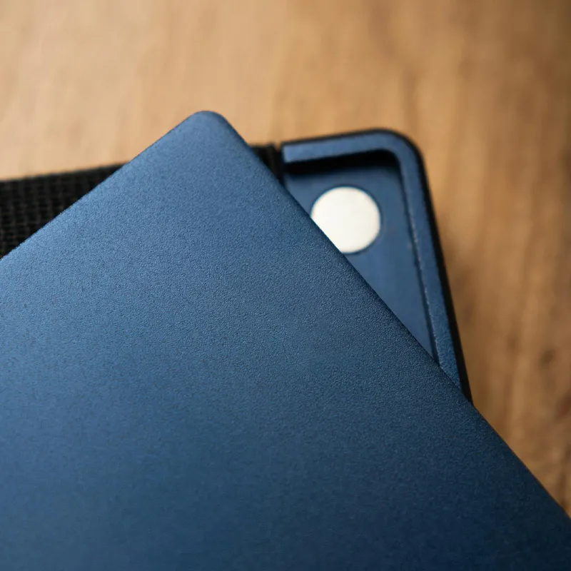 Close-up of a blue wallet with a metallic button on a wooden surface.