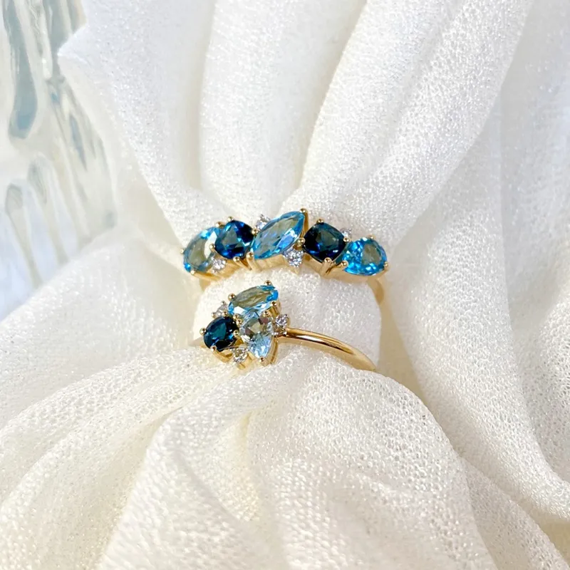 Two elegant rings featuring blue gemstones set in gold, displayed on soft white fabric.