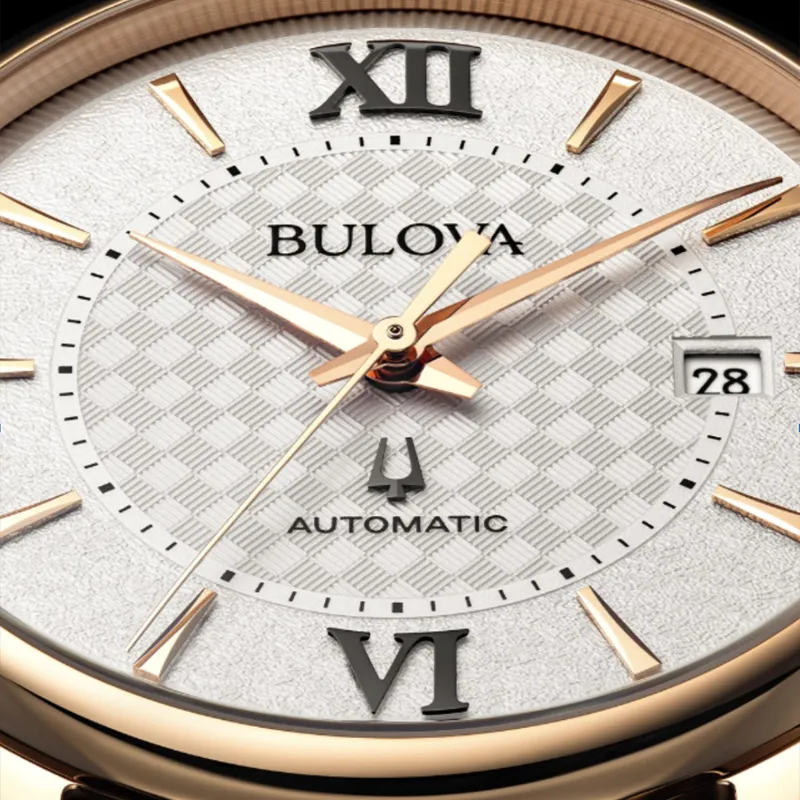 Close-up of a Bulova automatic watch with a textured silver dial, rose gold hands, and date display.