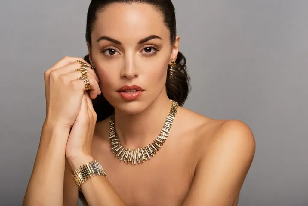 Model showcasing elegant gold jewelry including a necklace, bracelet, and earrings at Arezzo Jewelers in Elmwood.