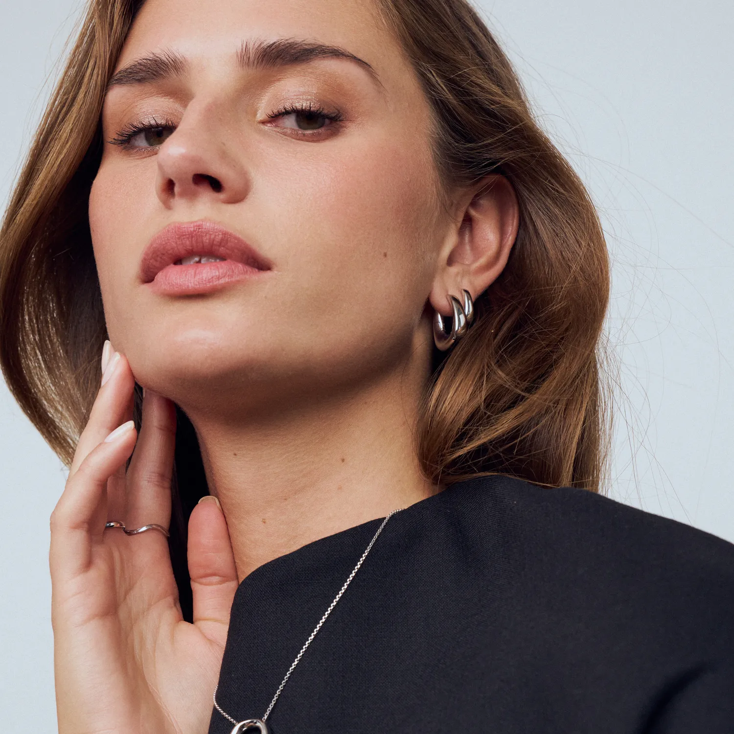 Model showcasing Sif Jakobs jewelry, featuring earrings and a necklace, promoting Arezzo Jewelers. Shop now at Arezzo Jewelers.