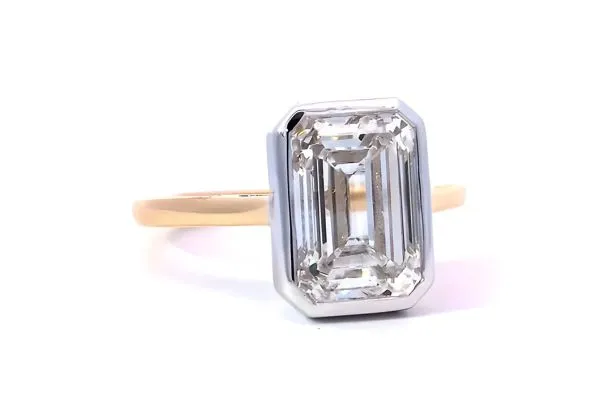 Elegant gold engagement ring with an emerald-cut center stone and diamond accents, inspired by Taylor Swift. Click to view.