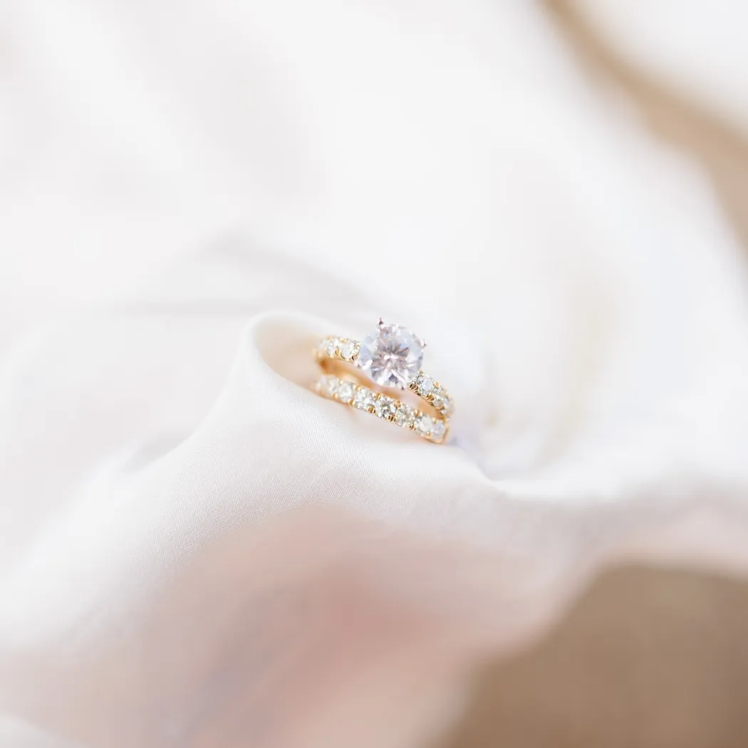 Elegant gold engagement and wedding rings on soft fabric, showcasing a sparkling diamond centerpiece.