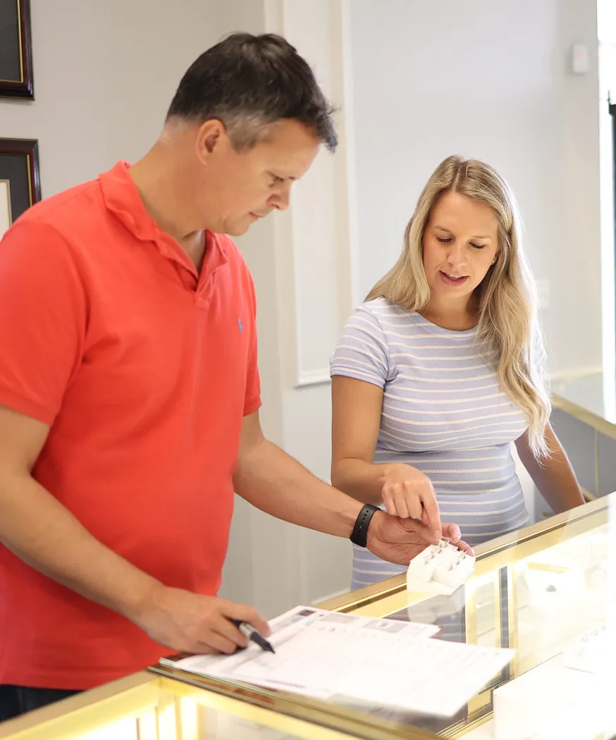 A man and woman examine jewelry together in a store, discussing options at Barnes Jewelers in Goldsboro.