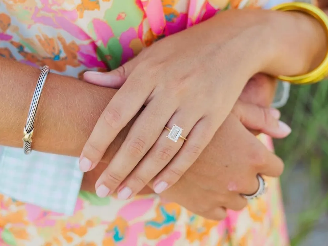Close-up of hands with a diamond engagement ring and bracelets.