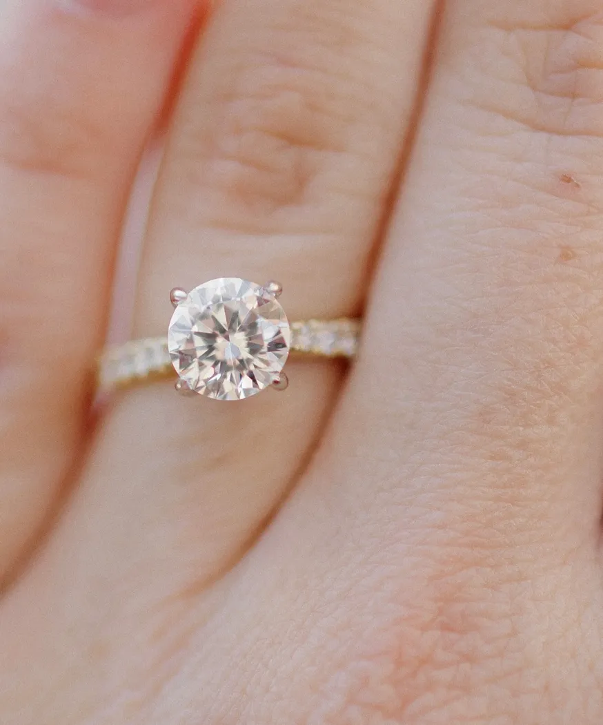 Close-up of a diamond engagement ring with a round center stone and a delicate band.