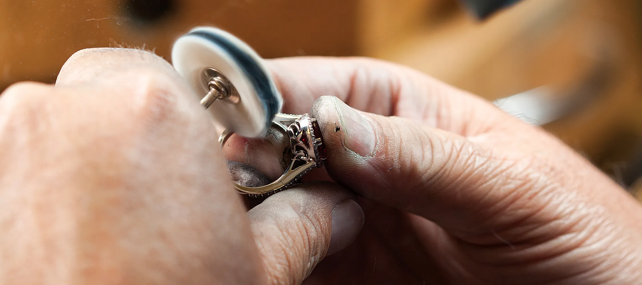 Jeweler polishing a ring with a buffing wheel.