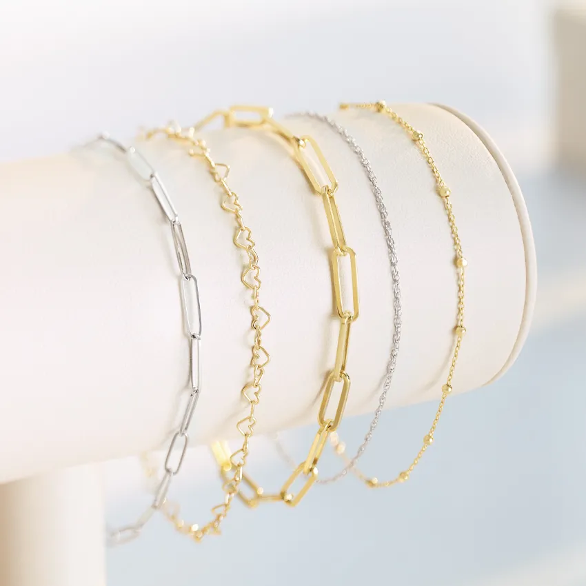 Five stylish bracelets in silver and gold displayed on a stand.