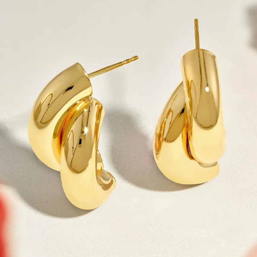 Gold sculptural earrings displayed on a light surface, showcasing a modern design.