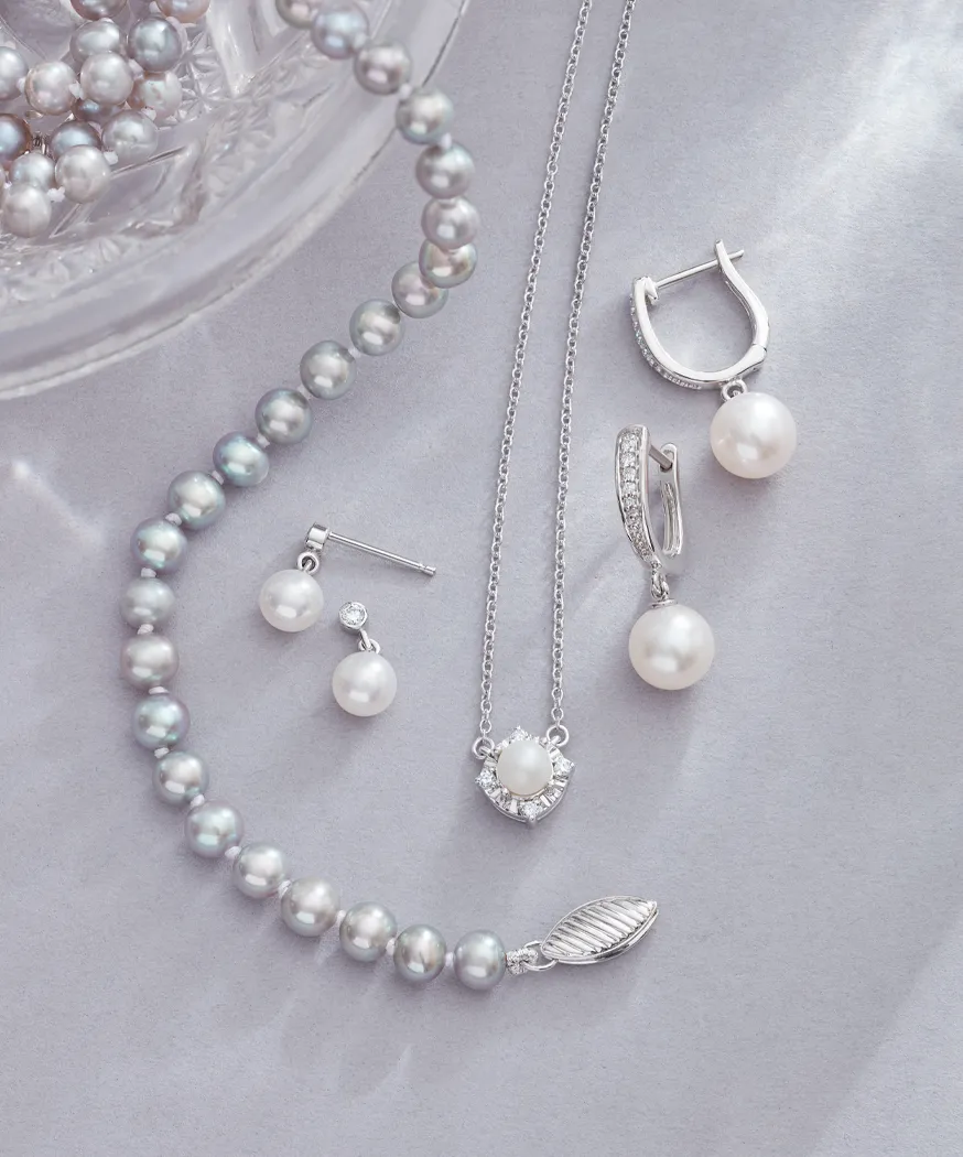 Elegant pearl jewelry set including earrings, necklace, and bracelet displayed on a soft background.