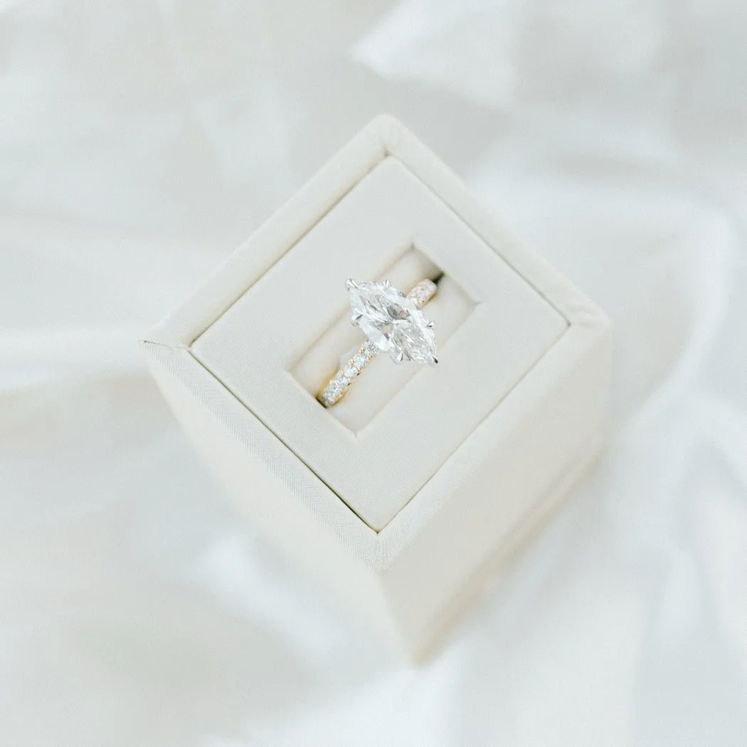 Elegant marquise diamond engagement ring in a cream box, displayed on soft fabric.