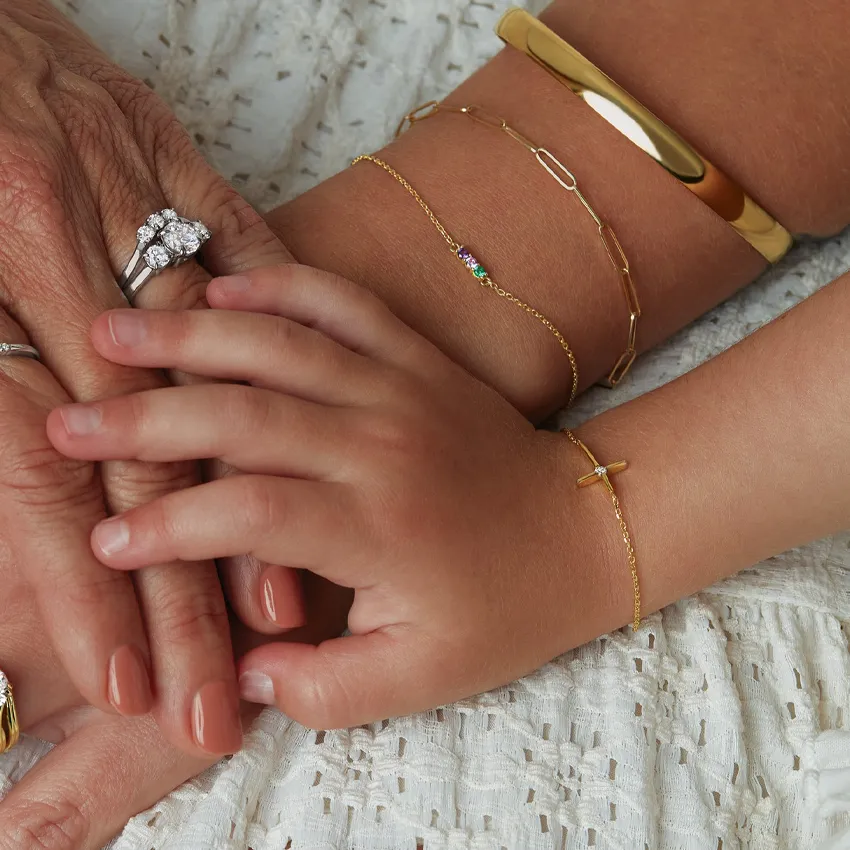 Three generations of hands adorned with elegant jewelry, showcasing a mix of rings and bracelets.