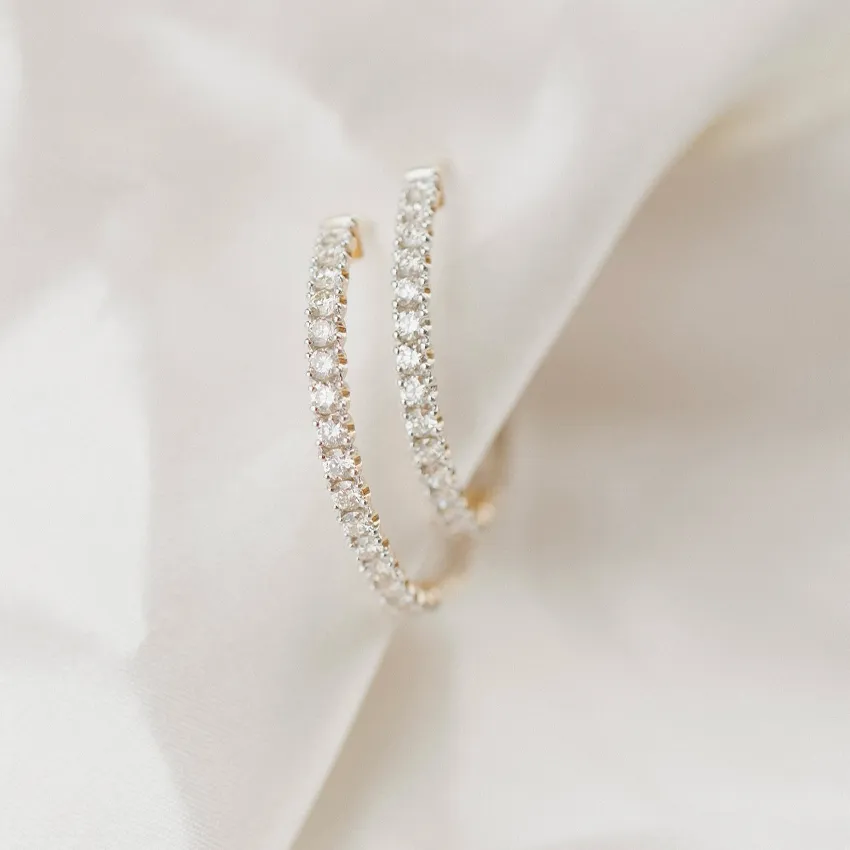 Elegant diamond hoop earrings on soft fabric background, showcasing sparkle and luxury.