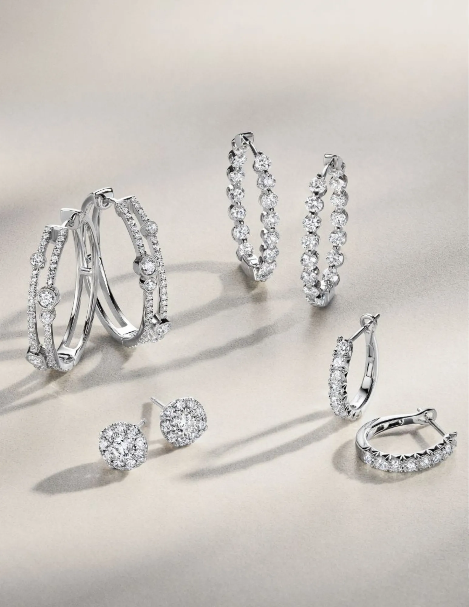 Model showcasing elegant jewelry, including rings and bracelets, against a textured white wall. Shop at Jim Bartlett Fine Jewelr