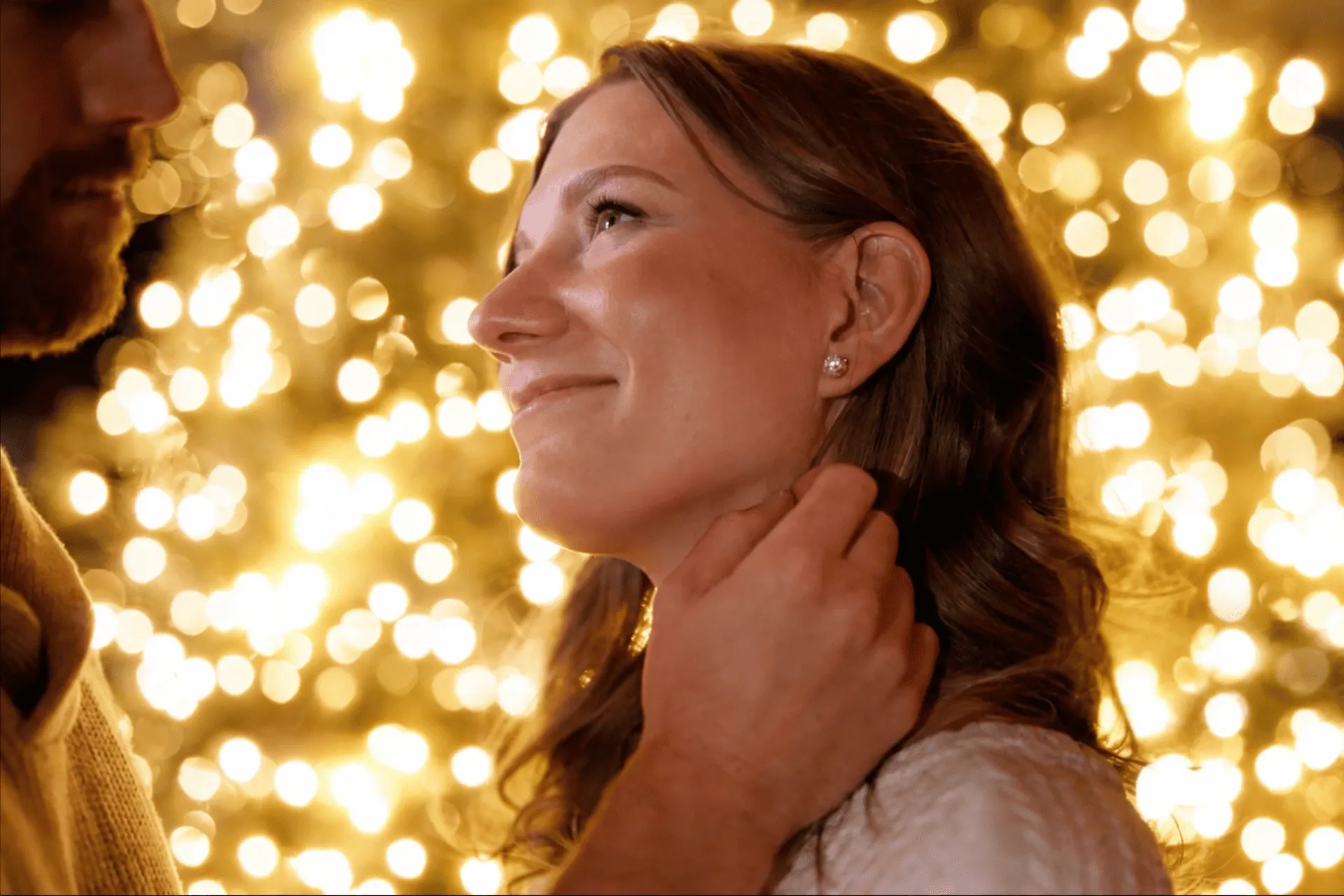 A woman smiling in front of glowing holiday lights