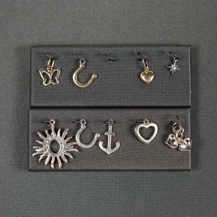 Gold and silver permanent jewelry charms on a black display